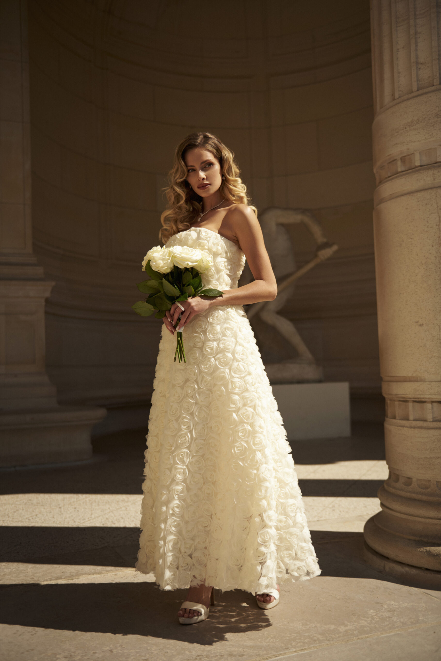 Bride in a floral wedding dress with soft makeup and long curls in Paris.